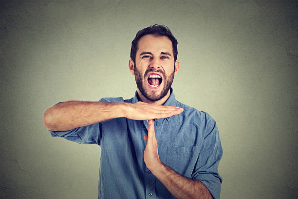 man showing time out hand gesture frustrated screaming stop Young man showing time out hand gesture, frustrated screaming to stop isolated on grey wall background. Too many things to do overwhelmed. Human emotions face expression reaction time out signal stock pictures, royalty-free photos & images