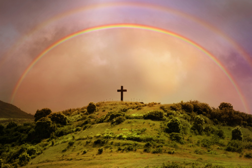 Rainbow over a cross on a hill in Maui, Hawaii.