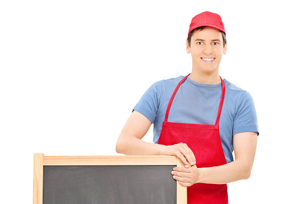 istock Man in apron standing behind a wooden blackboard 503318343