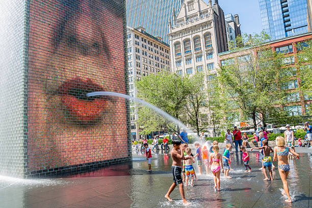 The Crown Fountain in Millenium Park, Chicago, Illinois Chicago, USA - August 22, 2015:   Chidlren playing in the Crown Fountains at Millenium Park.  This animated fountain attract young and old people.  Sight in both original and refreshing, this site is very popular espacially on days of heat waves and certainely the favorite workart of children in Chicago. millennium park chicago stock pictures, royalty-free photos & images