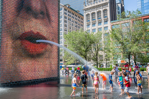 Chicago, USA - August 22, 2015:   Chidlren playing in the Crown Fountains at Millenium Park.  This animated fountain attract young and old people.  Sight in both original and refreshing, this site is very popular espacially on days of heat waves and certainely the favorite workart of children in Chicago.