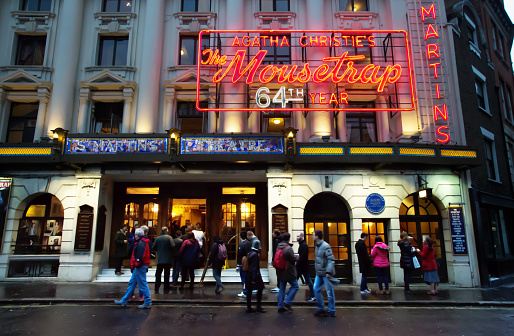 London, United Kingdom - January 02, 2016: front face of St.Martins Theater at dusk. On the building a big neon sign announcing a play by Agatha Christie: the Mousetrap. Some people are visible in front of the theater.