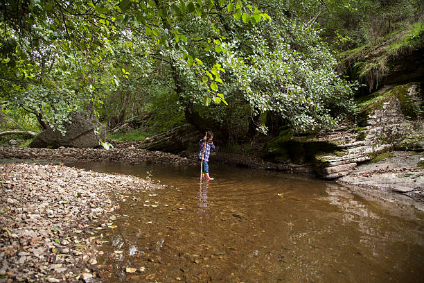 istock girl playing by river 503331434