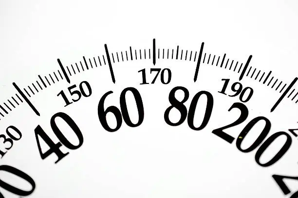 Bathroom scale numbers showing weight in pounds and kilograms.