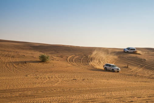 Dubai, UAE - November 1, 2013: All-terrain vehicle driving through the desert, in a recreational activity called desert safari or dune bashing.