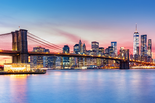 Brooklyn Bridge and the Lower Manhattan skyline under a purple sunset