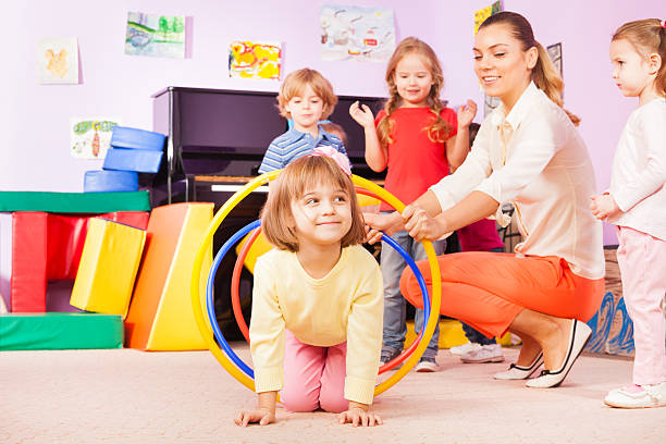 istock Girl crawl in plastic hoop, kindergarten group 503353410
