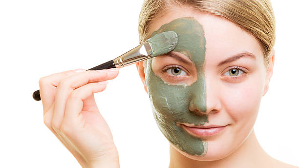 istock Woman applying with brush clay mud mask her face 503361228