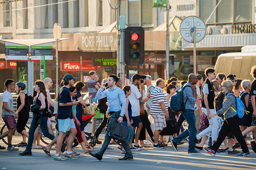 Melbourne, Australia - Dec 16, 2015: People walking across a busy crosswalk in downtown Melbourne at sunset