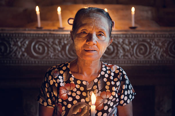 istock Burmese woman prayingwith candlelight 503362754