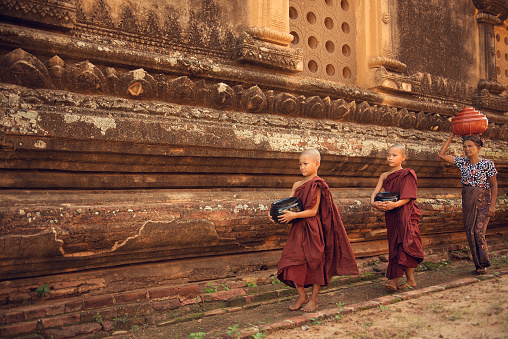 Southeast Asian young Buddhist novice monks walking morning alms in Old Bagan, Myanmar