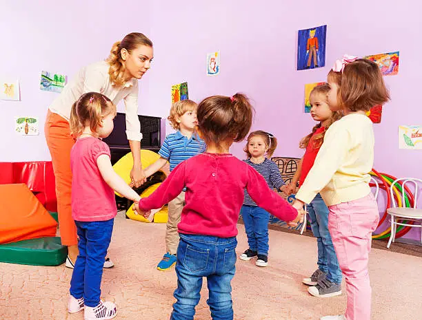 Photo of Teacher and group of kids in kindergarten