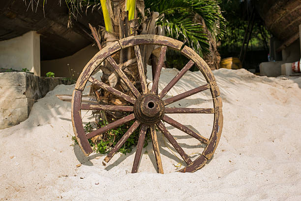 istock Old wooden wheel on sand 503363846