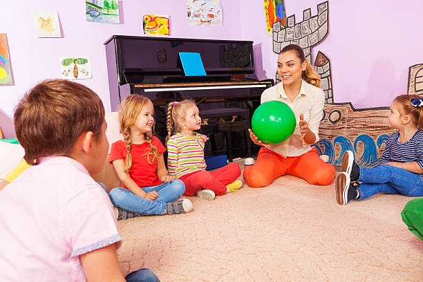 istock Teacher and kids sit in circle play with ball 503365846