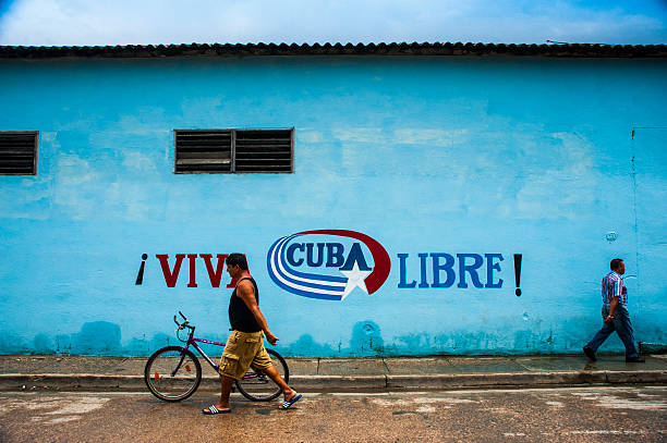 Two men walk past Viva Cuba Libre mural in Cuba stock photo
