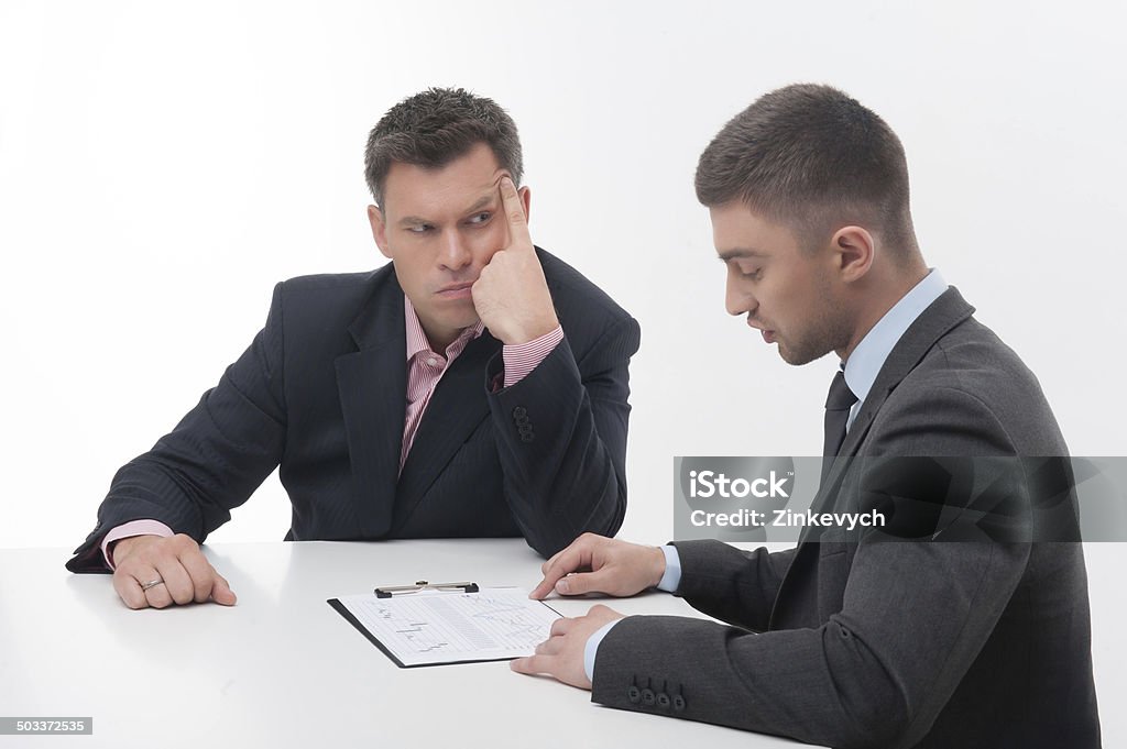 Two business people in elegant suits, chief and employee, holdin Two business people in elegant suits, chief looking suspicious at employee, holding clipboard with papers isolated on white background Adult Stock Photo