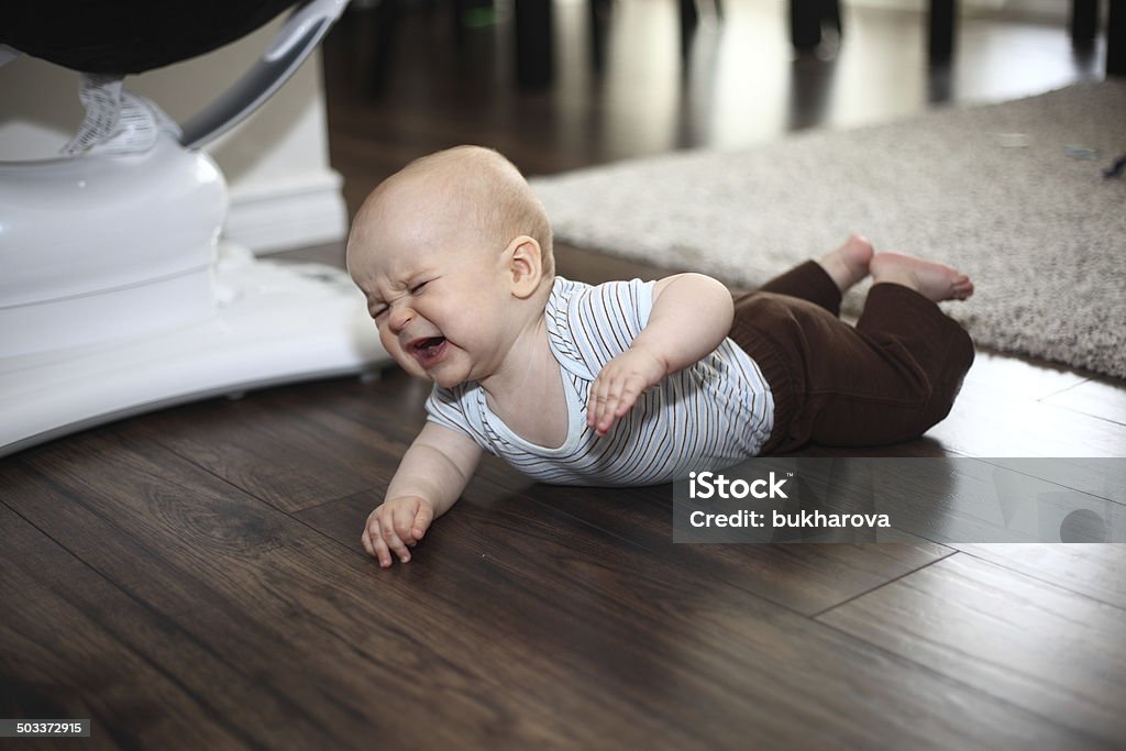 Crying baby on the floor An image of a crying Caucasian baby boy lying on the floor on his tummy with one raised arm. See more in my profile Crying Stock Photo