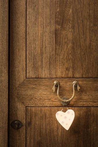 An old wooden door with a white heart hanging on its knocker