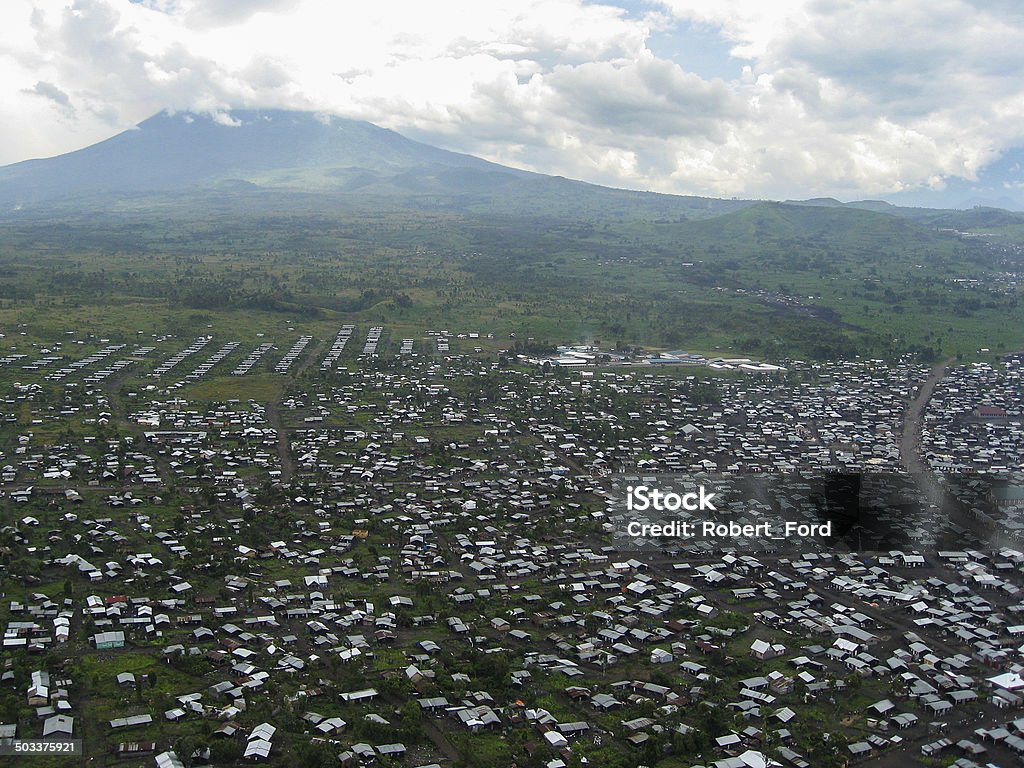 Large Refugee camp near Goma Republic of Congo and Volcano Large Refugee camp on a recent volcanic lava field near Goma Republic of Congo and active Volcano in the background within the Virunga National Park and part of the Virunga Mountains Refugee Camp Stock Photo