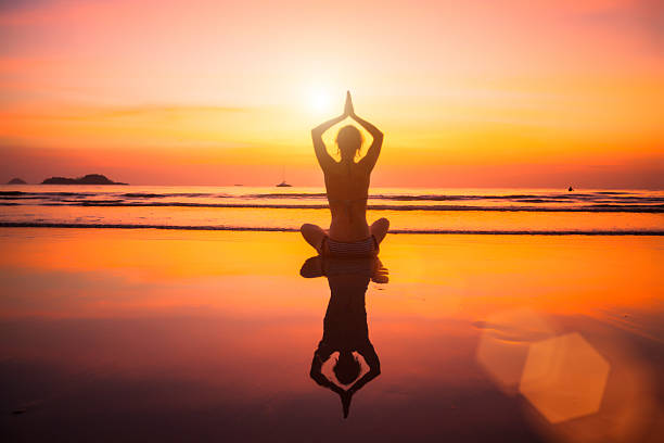 istock Woman meditating on the beach at sunset. 503377859