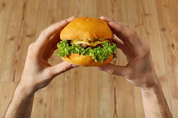 salle à manger fast-food. mains tenant hamburger. point de vue. nutrition. - acute pain photos et images de collection