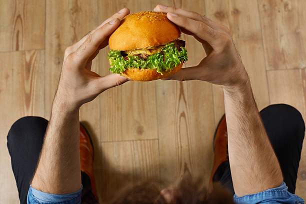 Eating Fast Food. Hands Holding Hamburger. Point Of View. Nutrition