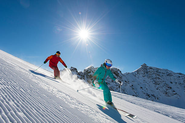 alpine skiing in the alp mountains ski downhill with sun in the background skiing stock pictures, royalty-free photos & images