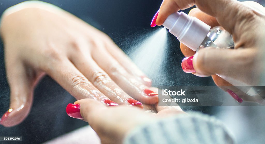 Manicure treatment. Closeup of manicure professionalist spraying oil onto female client's hands after manicure procedure. It's special type of oil that moistens fingernails and skin around them. Hair Gel Stock Photo