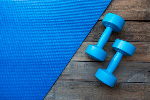 dumbbells and yoga mat on wood table