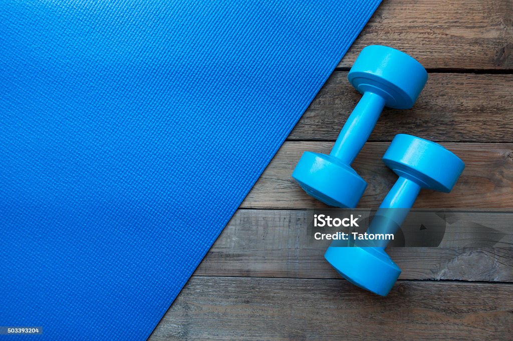 dumbbells and yoga mat on wood table Exercise Mat Stock Photo