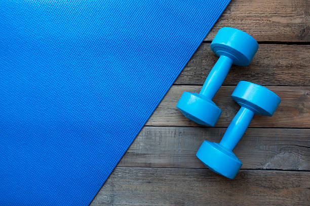 dumbbells and yoga mat on wood table dumbbells and yoga mat on wood table mat stock pictures, royalty-free photos & images