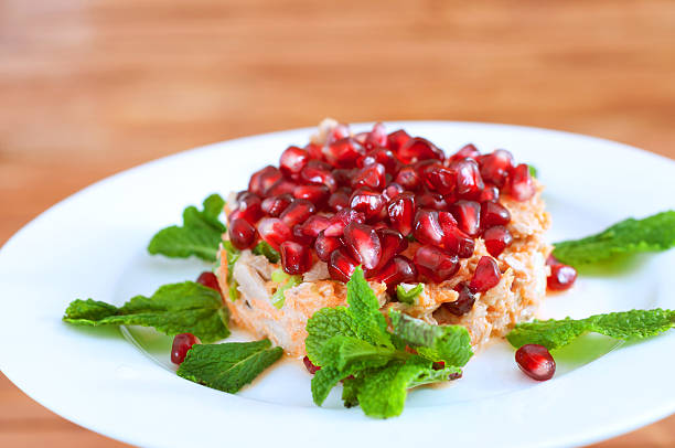 Fresh summer salad with pomegranate, canned tuna fish, carrots and mint leaves