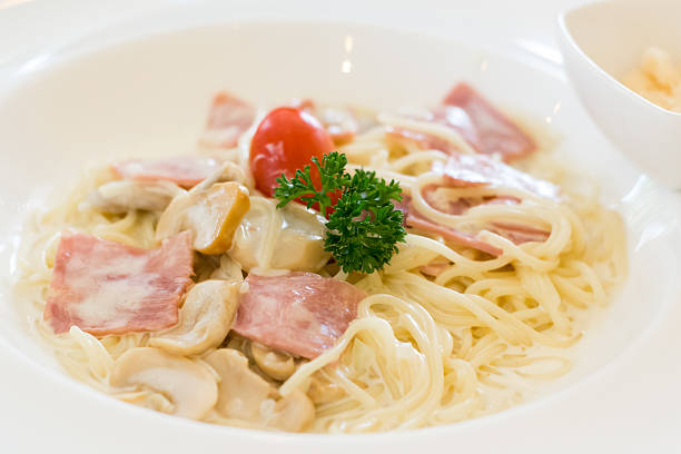 spaghetti carbonara mit schinken und tomaten in weiß schüssel - pasta cabonara stock-fotos und bilder