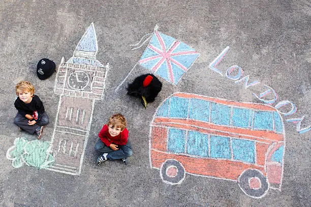 Photo of Two little kids with London picture drawing with chalks