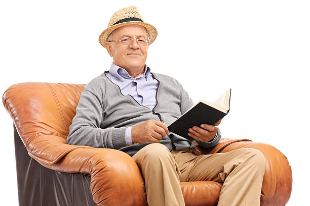 istock Senior holding a book seated in an armchair 503419762