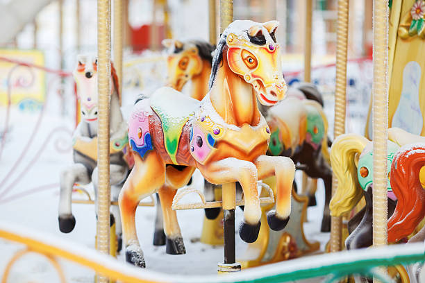 Fairground carousel horses during the day covered with snow in stock photo