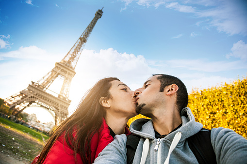 Couple taking a selfie in Paris under the Eiffel Tower during a love vacation.