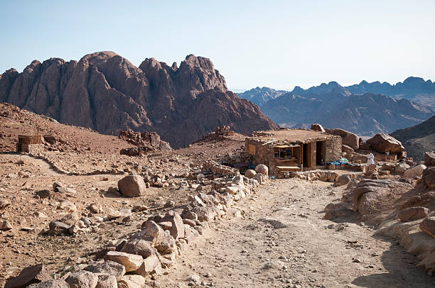 Mount Sinai, Egypt - May 24, 2010: A Bedouin stands outside his small store and cafe located on the trail connecting the summit of Mount Sinai to St. Catherine's Monastery in Sinai, Egypt. On the left, a path leads to an outhouse.
