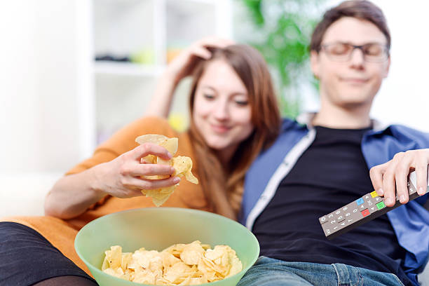 istock Beautiful young couple watching tv and eating on a sofa 503433739