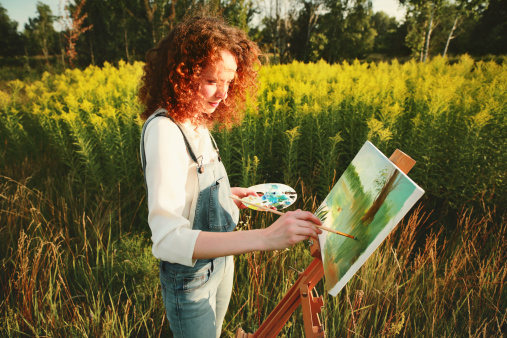 Young woman painting landscape in the open air.