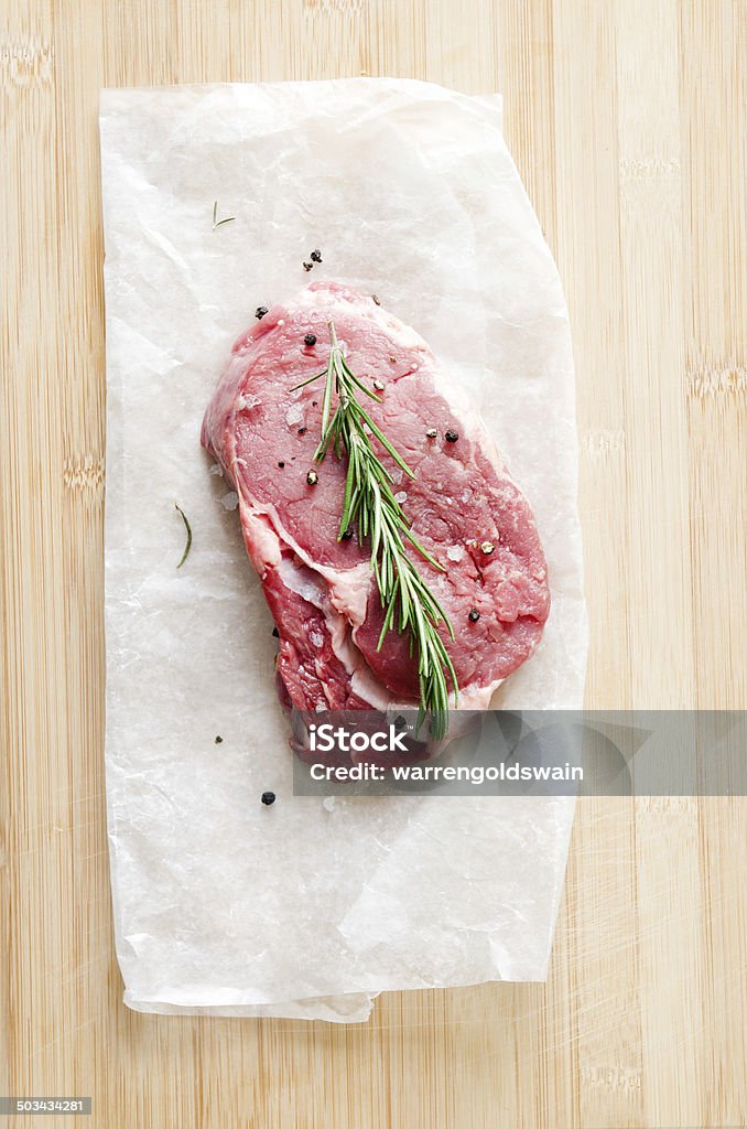 Raw steak on wooden surface with salt and pepper Raw ribeye steak on wooden board, overhead perspective Directly Above Stock Photo