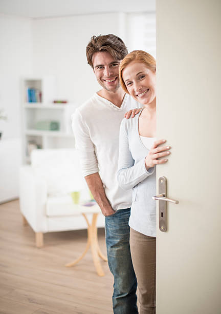 istock Cheerful couple inviting people to enter in home 503439677