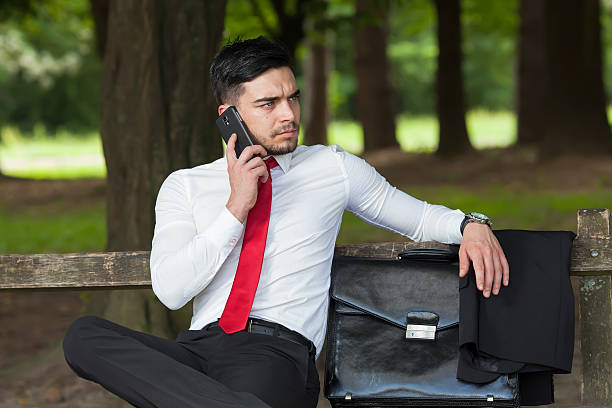 Young business man talking on smart phone in city park stock photo