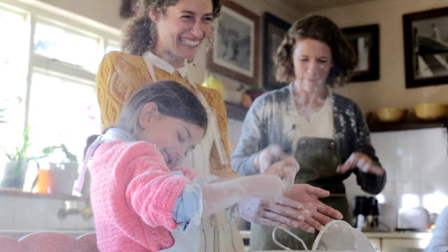 Multi-generation family playing with flour in kitchen