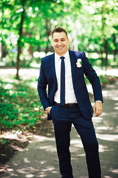 istock gorgeous elegant happy groom standing light on a background trees 503461830