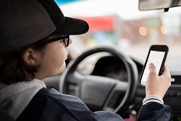 istock teen scrolling through phone in drivers seat 503483294
