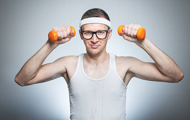 Nerd with dumbbells exercising stock photo