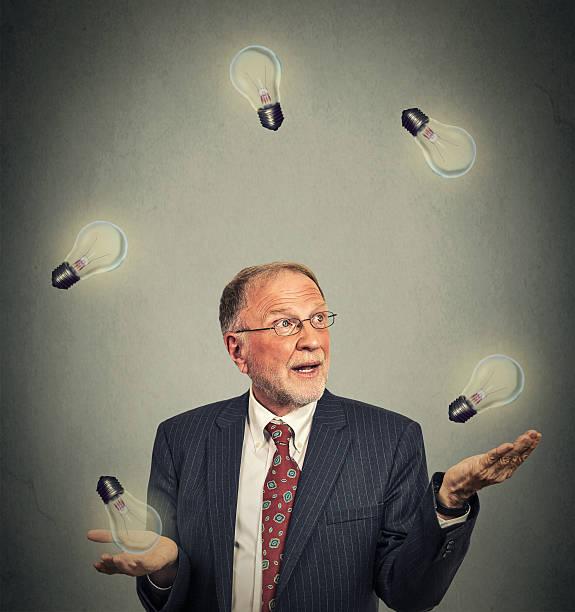 uomo d'affari senior in abito fare il giocoliere con lampadine - juggling efficiency skill businessman foto e immagini stock