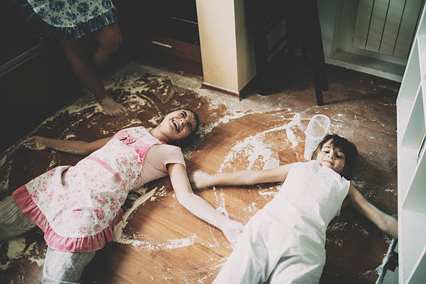 Two children lying on floor in kitchen Two children lying on floor covered with flour in kitchen chaos stock pictures, royalty-free photos & images