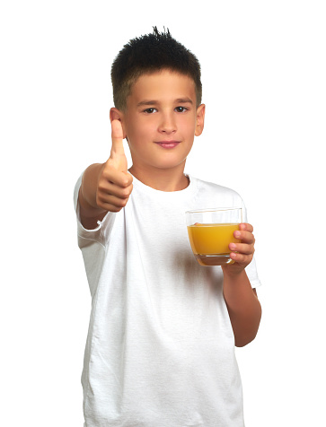 Child boy holds a glass with orange juice and shows yes isolated on white background